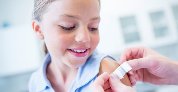 Girl looking as doctor places bandaid on arm